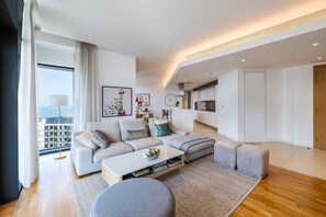 A modern living room with a sectional sofa, a coffee table, and a view of the city.