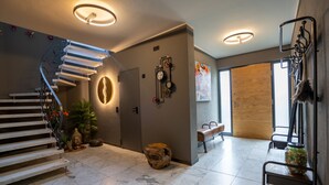 A modern interior with a spiral staircase, a wooden door, a wall-mounted clock, and a bench. - 5 Bedroom Villa in Mendig (Mendig)