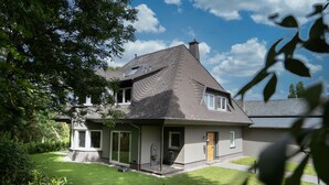 A two-story house with a sloped roof, a front porch, and a well-maintained lawn. - 5 Bedroom Villa in Mendig (Mendig)