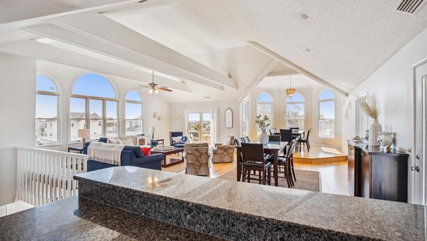 A spacious living area with a high ceiling, large windows, and a central island with a granite countertop. - 1525 - Pampa Hill - Poolside Corolla Getaway w/ Theater Room (Corolla)