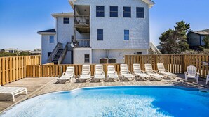 A two-story house with a swimming pool, wooden deck, and lounge chairs. - 1525 - Pampa Hill - Poolside Corolla Getaway w/ Theater Room (Corolla)