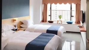 A hotel room with two beds, a window with curtains, a small table with a plant, and a television on the wall. - Feilisi Apartment (Zhongshan Yuelai South Road) (Zhongshan)
