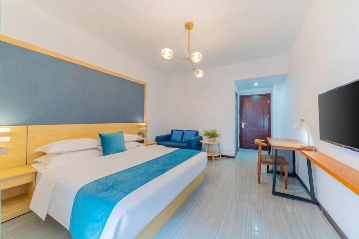 Una habitación de hotel moderna con una cama grande, un escritorio y un televisor.