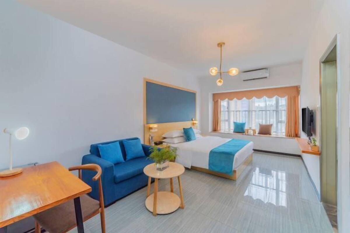 Una habitación de hotel moderna con una cama, un sofá azul, una mesa de madera y una mesita redonda.