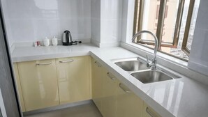 A kitchen with two sinks, a window, and a view of buildings outside. - Feilisi Apartment (Zhongshan Yuelai South Road) (Zhongshan)