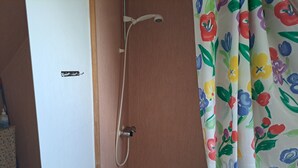 Une douche avec un tuyau d’arrosage et un rideau à motifs floraux.