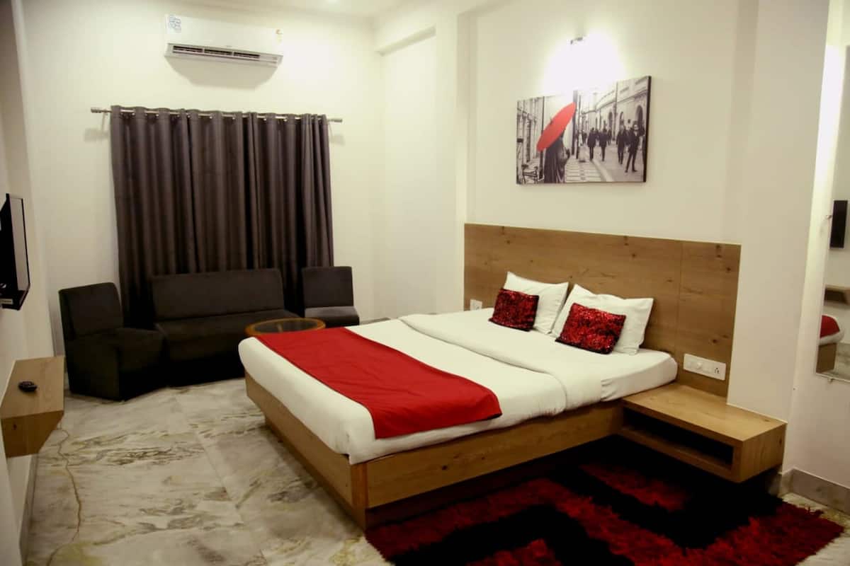 Um quarto com uma cama, um sofá, um tapete vermelho e um quadro na parede.