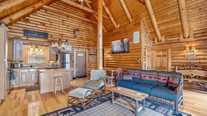 A log cabin interior with a kitchen, bar area, and seating. - Overlook at Sleepy Creek -secluded, creek access, grill, wifi, deck, game room (Berkeley Springs)