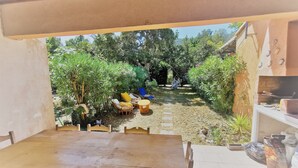 An outdoor patio area with a wooden table and chairs, surrounded by lush greenery and a hammock. - 10 MNS from PORTO VECCHIO MINI VILLA WITH SEASIDE LAND MER-6 People (Saint Lucie de Porto Vecchio)