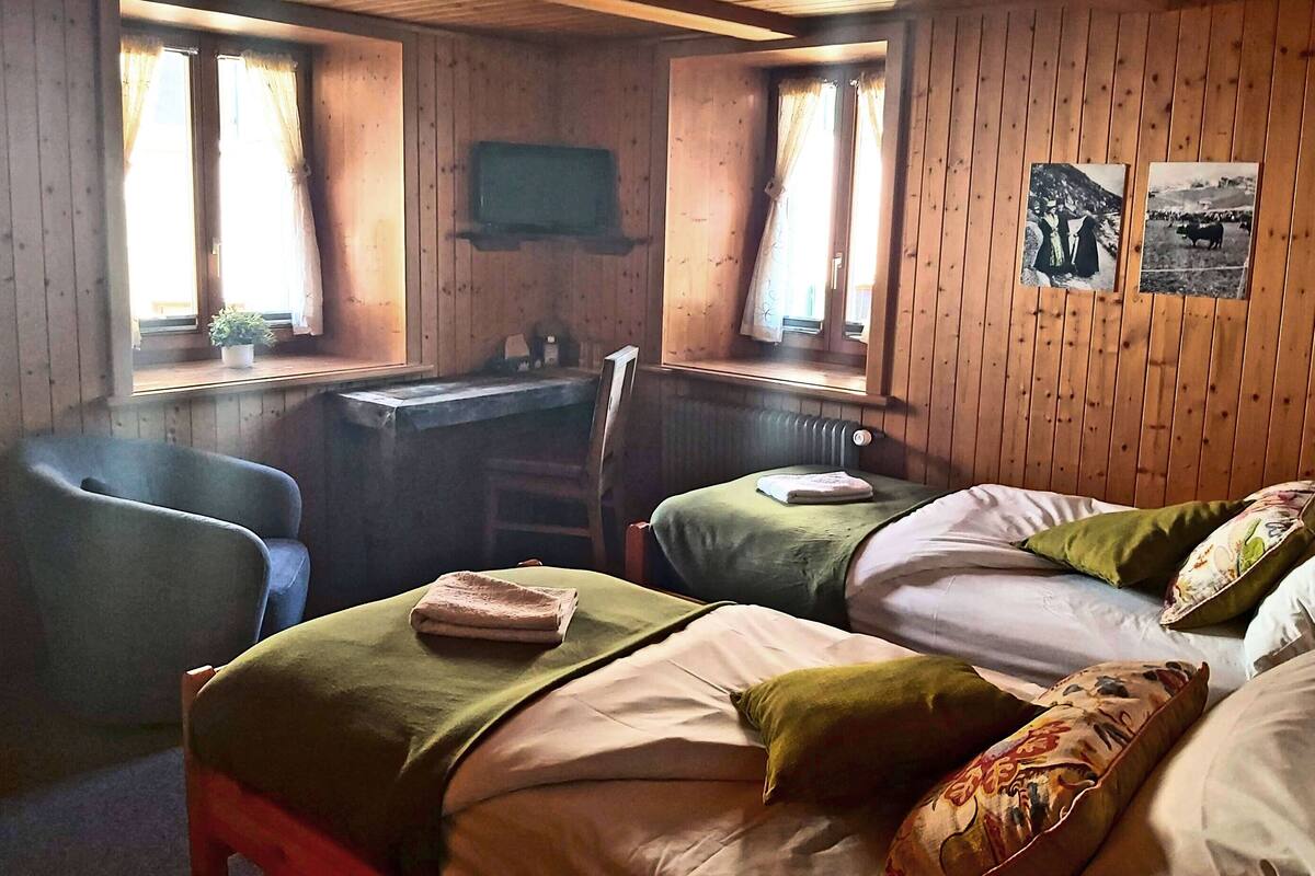 A cabin-style room with two beds, a desk, and a chair.