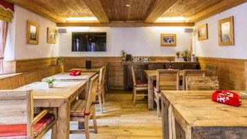 A rustic wooden interior with wooden benches and tables, framed pictures on the walls, and a bar area.