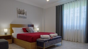 Une chambre à coucher avec un lit, des tables de chevet, un banc et un tableau au mur.