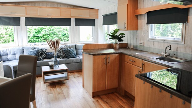 A compact kitchen with wooden cabinets, a built-in sink, and a window overlooking greenery.