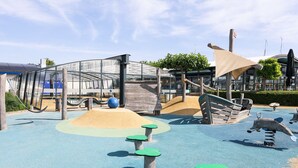 A playground with climbing structures, slides, and a sandy play area.