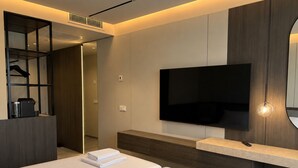 A modern hotel room with a large bed, a flat-screen TV mounted on the wall, a built-in coffee machine, and a walk-in closet. - Wabi Hotel - Beauty & Dental Center (Sopron)