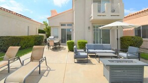 A two-story building with a patio area featuring outdoor furniture and a fire pit. - Desert Princess Townhouse Retreat (Cathedral City)