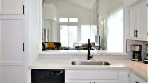 A modern kitchen with white cabinetry, a black faucet, and a built-in dishwasher. - Desert Princess Townhouse Retreat (Cathedral City)