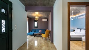 Un intérieur moderne avec un canapé, un fauteuil, un lit et un lustre.
