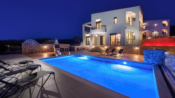 Une villa moderne dotée d’une piscine, d’un espace salon extérieur et d’un mur en pierre.