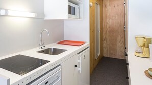 A compact kitchen with a sink, stove, microwave, and a small refrigerator.
