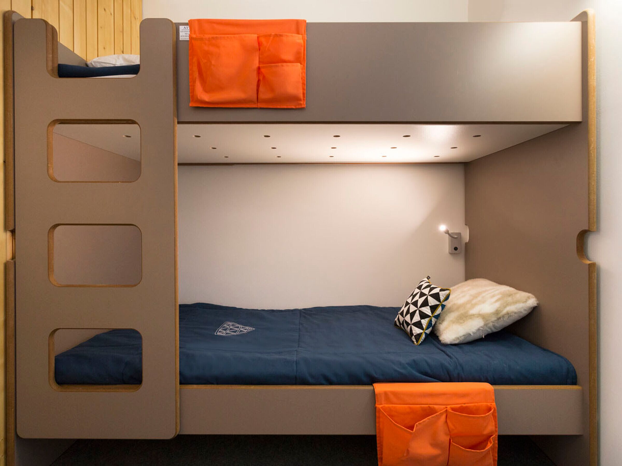 Un lit superposé avec un lit en bas et un lit en haut. Un oreiller à motifs géométriques se trouve sur le lit du bas.