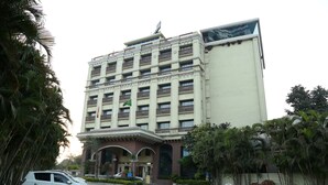 A multi-story hotel with a central entrance, surrounded by palm trees and a paved driveway. - HOTEL ANS INTERNATIONAL (Raigarh)