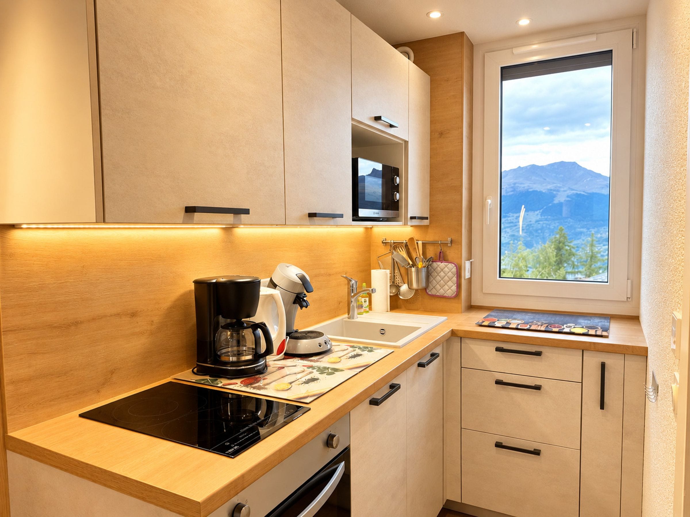 A modern kitchen with a built-in stove, a coffee maker, and a window with a mountain view.