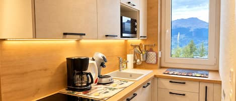 A modern kitchen with a built-in stove, a coffee maker, and a window with a mountain view.
