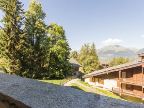 Ein Berggasthof mit steinverkleideter Fassade, Holzbalkonen und Blick auf den umliegenden Wald und die Berge.