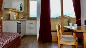 Cocina compacta con comedor, cama y vistas a las montañas.