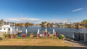 A waterfront property with a dock, a boat, and a view of houses across the water.