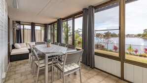 A dining area with a table and chairs, a bench, and a view of a lake.