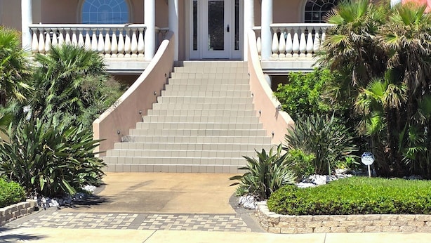 A two-story house with a central entrance, a balcony with balustrades, and a staircase leading to the entrance. - OceanView,3500sqft,60sec Beach Access! 4 bedrooms with 4 ensuite baths&Elevator! (South Padre Island)