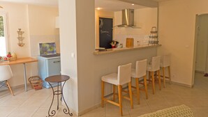 A compact kitchen with a dining area, a small refrigerator, and a chalkboard with writing. - Air conditionned house in a quiet village private pool in large closed garden  (Azille)