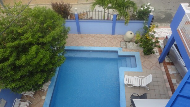 A rooftop pool with a blue border, surrounded by white lounge chairs and a potted plant. - King Suite with Kitchenette at Bellissimo (Buccoo)
