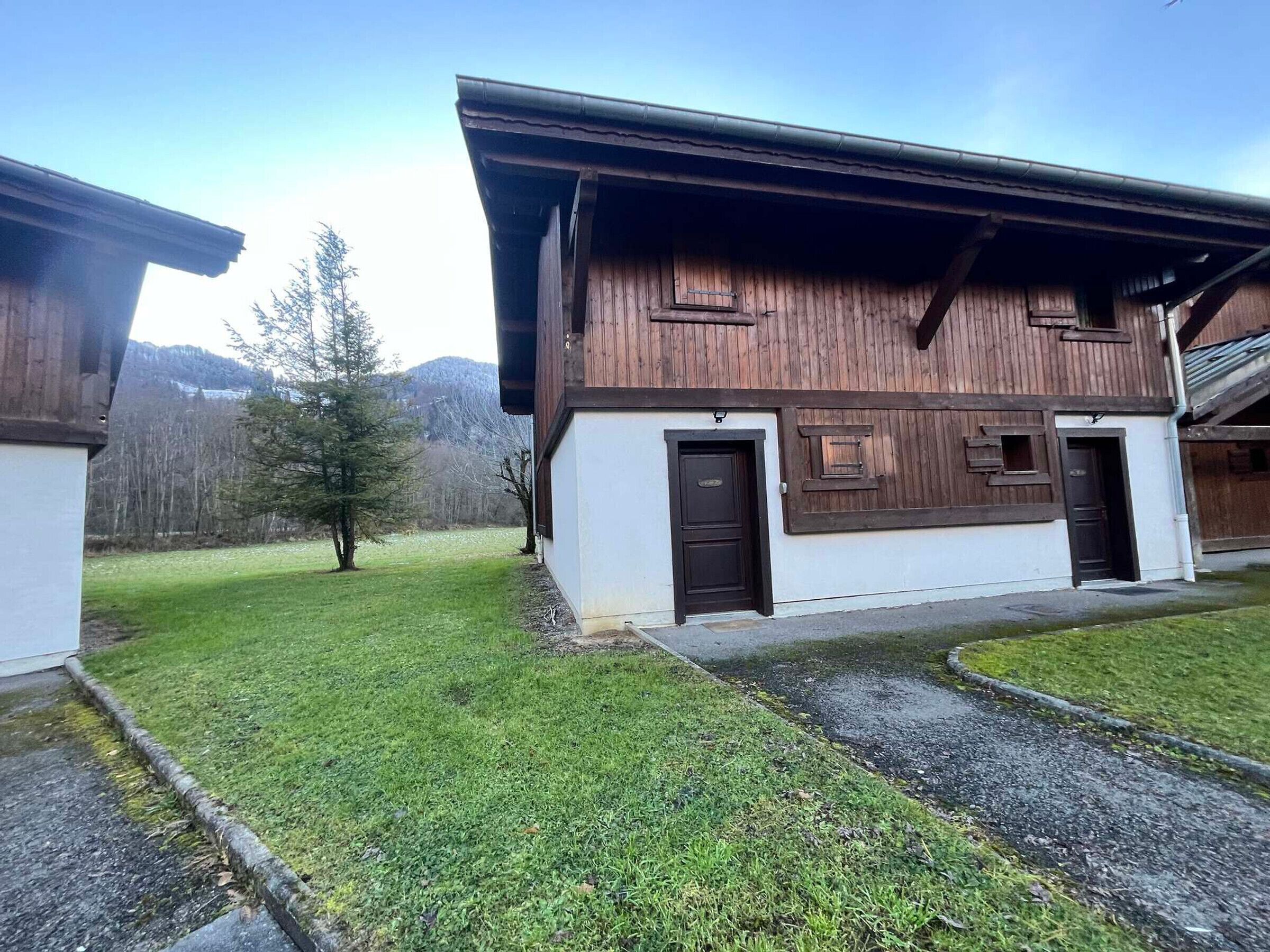 A wooden building with a white lower section and a black door.