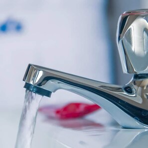 Gros plan d’un robinet chromé où coule de l’eau.