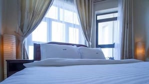 A hotel room with a large bed, curtains, and a window with blinds. - DAKS HOTEL KIRINYA (Kampala)