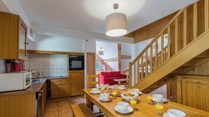 Une cuisine avec des meubles en bois, une table à manger dressée pour le petit-déjeuner et un escalier menant à un autre niveau.