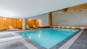 Une piscine avec des chaises longues et un mur en pierre.