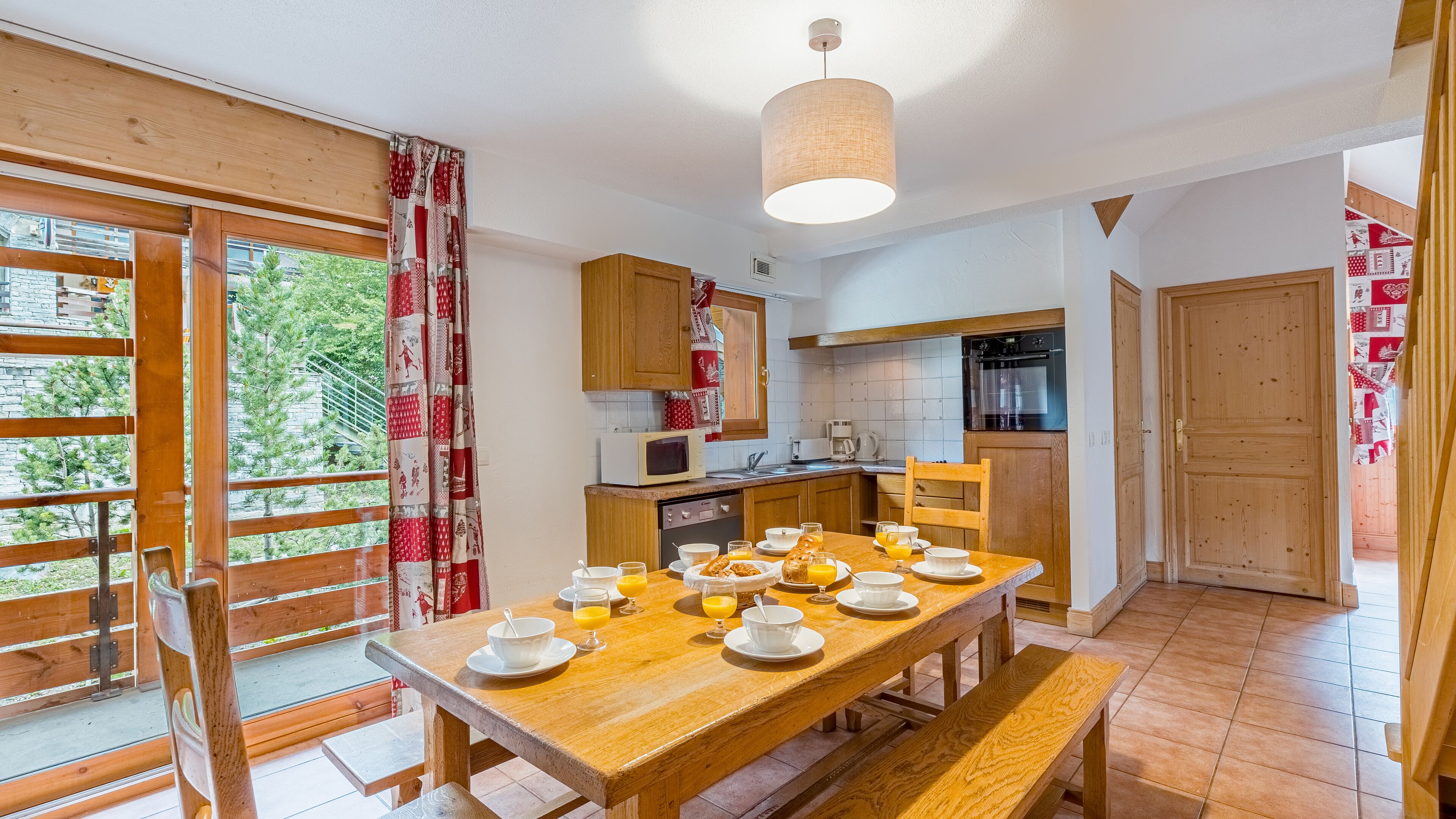 A cozy kitchen with wooden cabinets, a dining table set for breakfast, and a view of the outdoors.