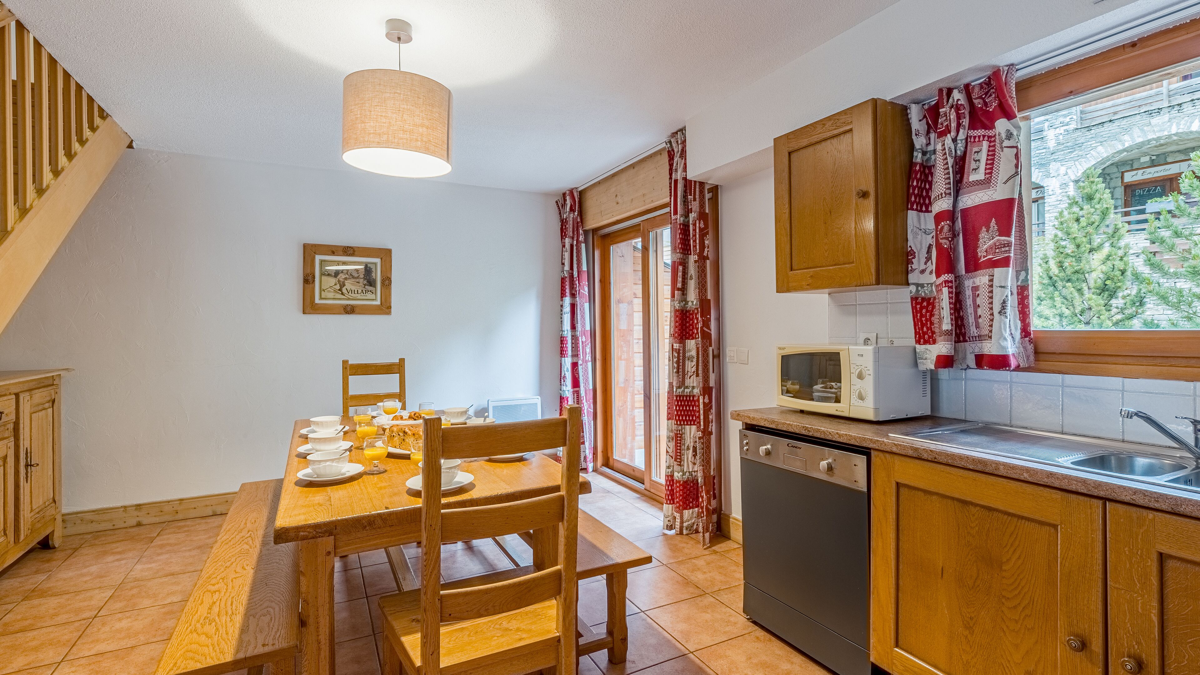 A kitchen with wooden cabinets, a dining table with chairs, a microwave, and a dishwasher.