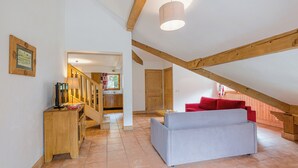 Une pièce mansardée spacieuse avec un escalier en bois, un canapé et un coin repas.