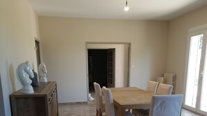 Un'ampia sala da pranzo con un tavolo e sedie in legno, un divano rosso e un armadio con oggetti decorativi.