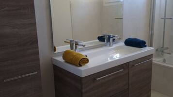 Een bad/douchecombinatie, een haardroger, handdoeken, zeep