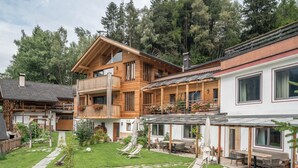 Ein zweigeschossiges Holzhaus mit Balkon, Terrasse und Garten.