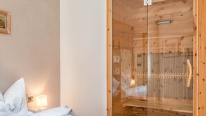 Ein Holzhütten-Zimmer mit Bett, einer Holzsauna und einer Glashaube.