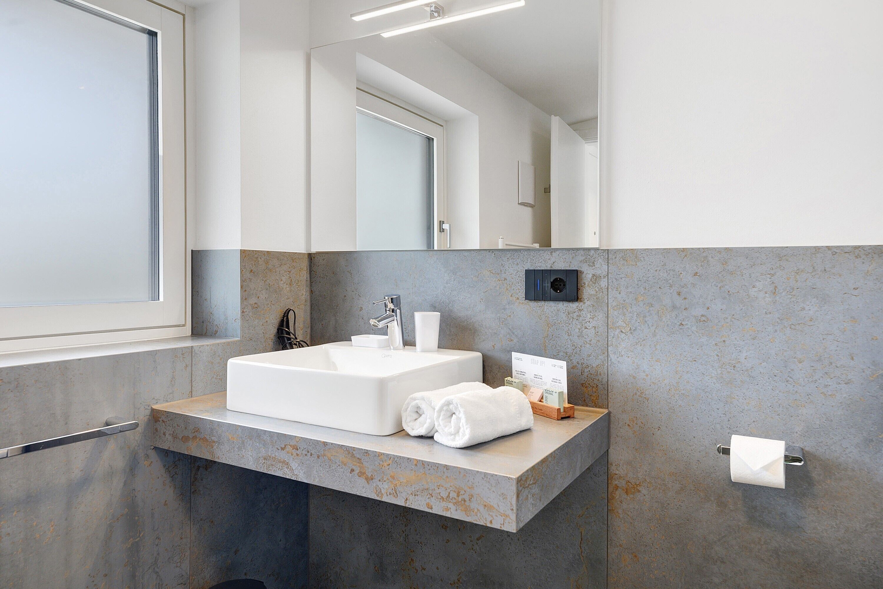 Een moderne badkamer met een grote wastafel, een spiegel en een handdoekhouder.