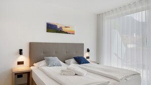 Een tweepersoonsbed met hoofdbord, twee nachtkastjes, een wandlamp en een schilderij.