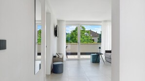 Een modern interieur met een grote schuifpui naar een balkon, een flatscreen televisie aan de wand en een minimalistische zithoek.